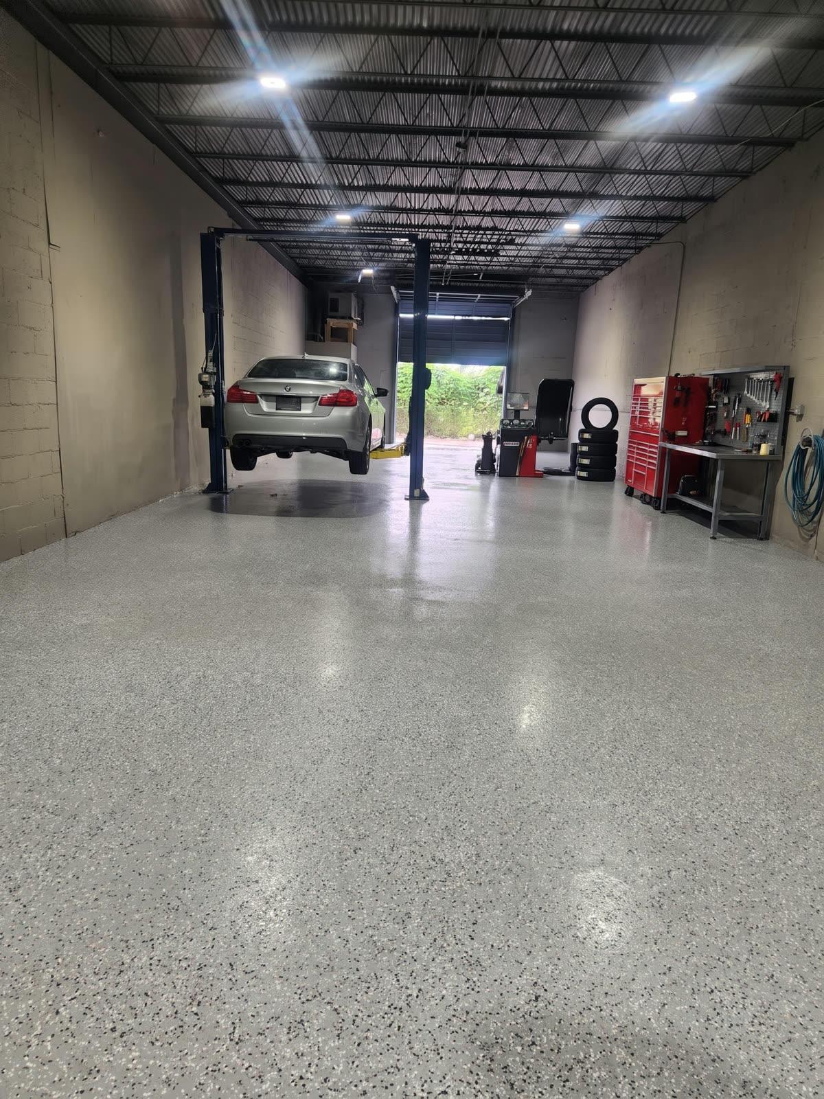 AI visualization: the bay set up as an auto repair shop with a car lift and tool chests