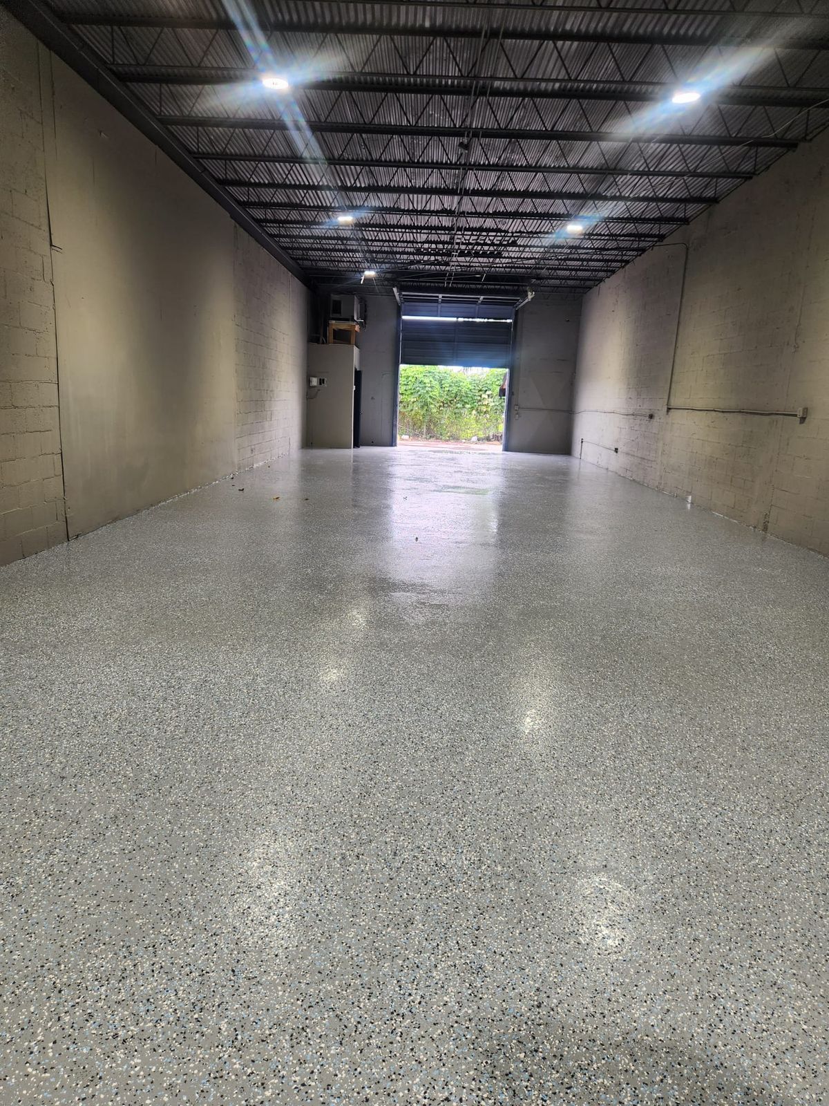Inside the warehouse bay: epoxy floor, LED lights and open roll-up door